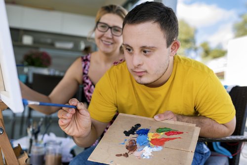 Jugendlicher malt mit Farben während eines Kunstprojektes.