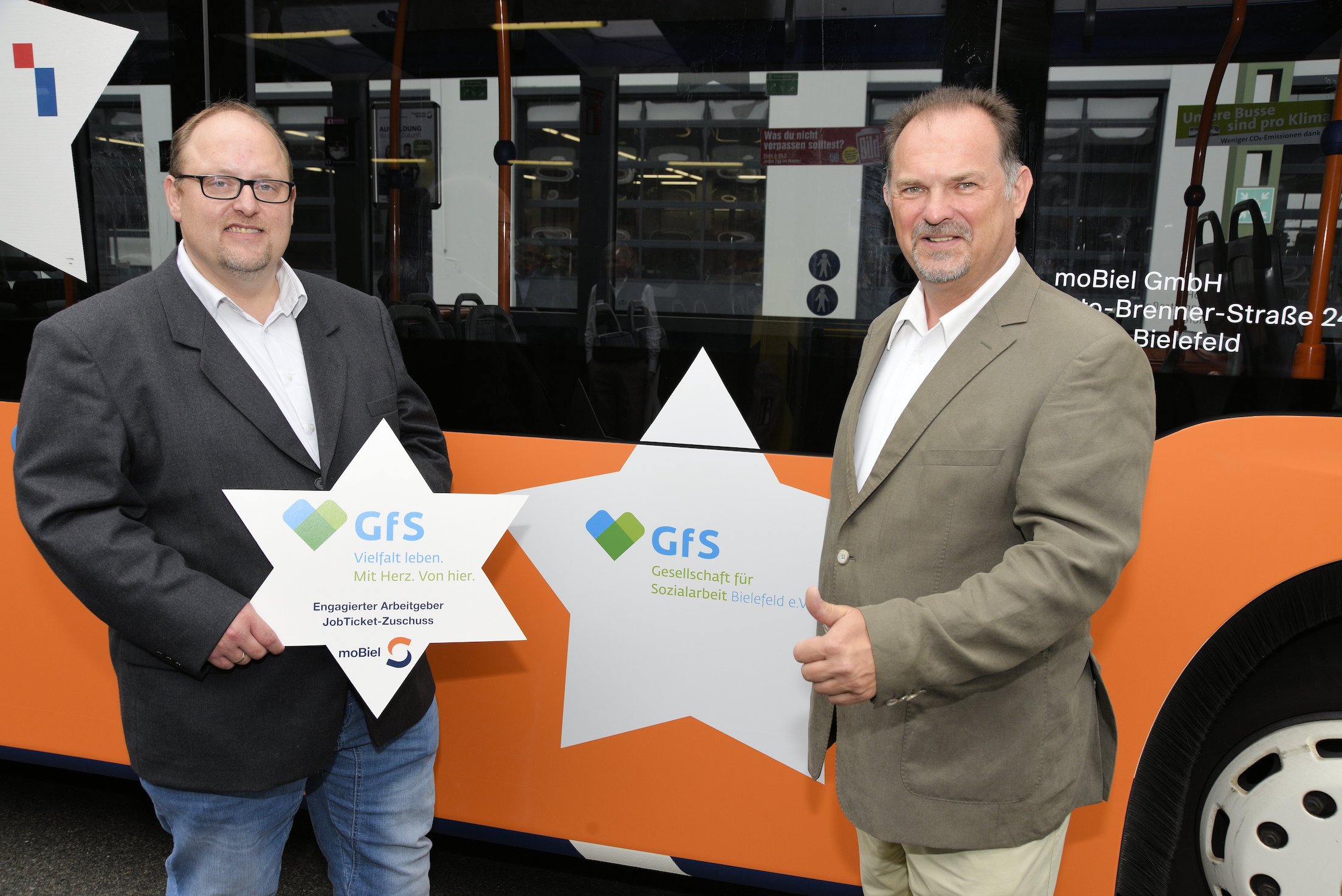 Thomas Brandauer und Jens Grabbe von der GfS Bielefeld vor dem Bus mit Jobticket Werbung